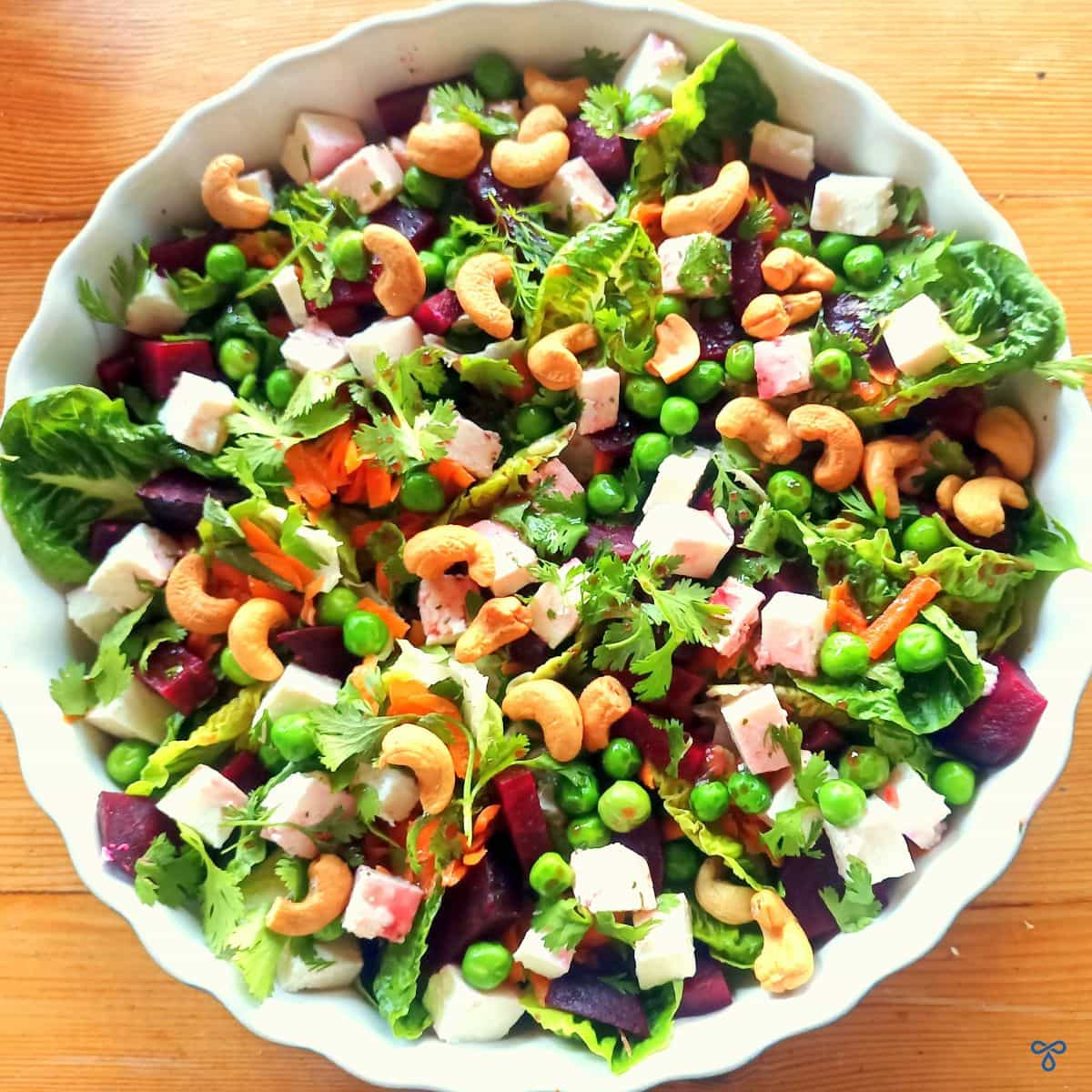 A bowl of salad taken from above. Pea and feta cheese with beetroot and cashews.