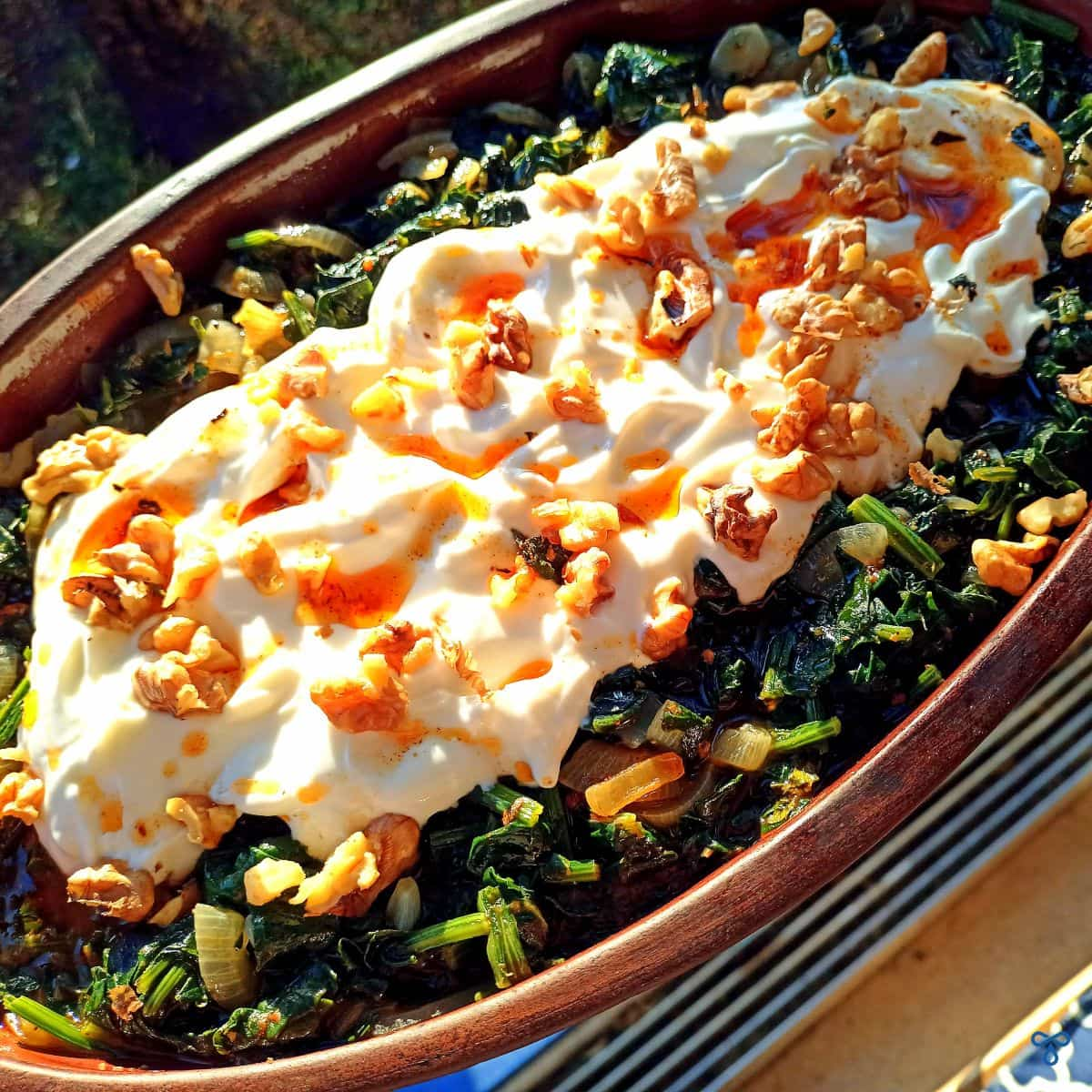 Cooked spinach borani topped with yoghurt and walnuts